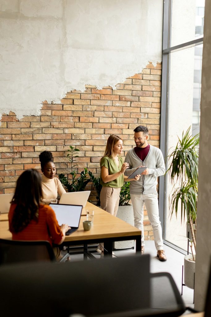 Young multiethnic startup team working by the brick wall in the industrial style office